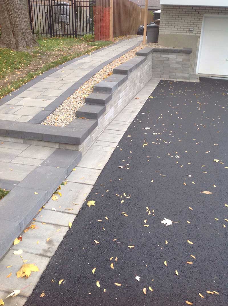 Beautiful paver Bborder with asphalt in the middle. Paver walkway with a black border all around.